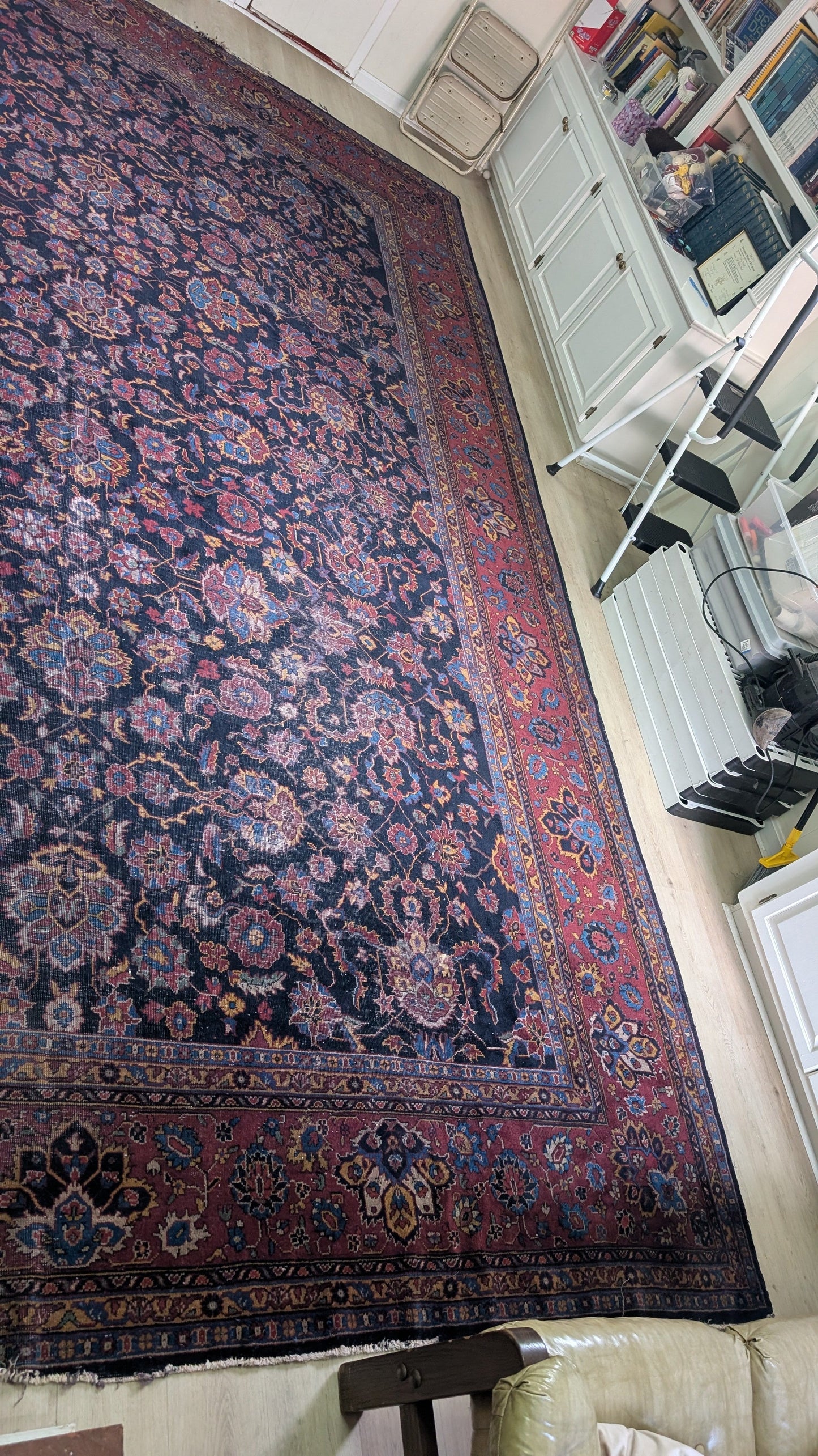Antique Turkish rug with intricate patterns on a floor in a room.